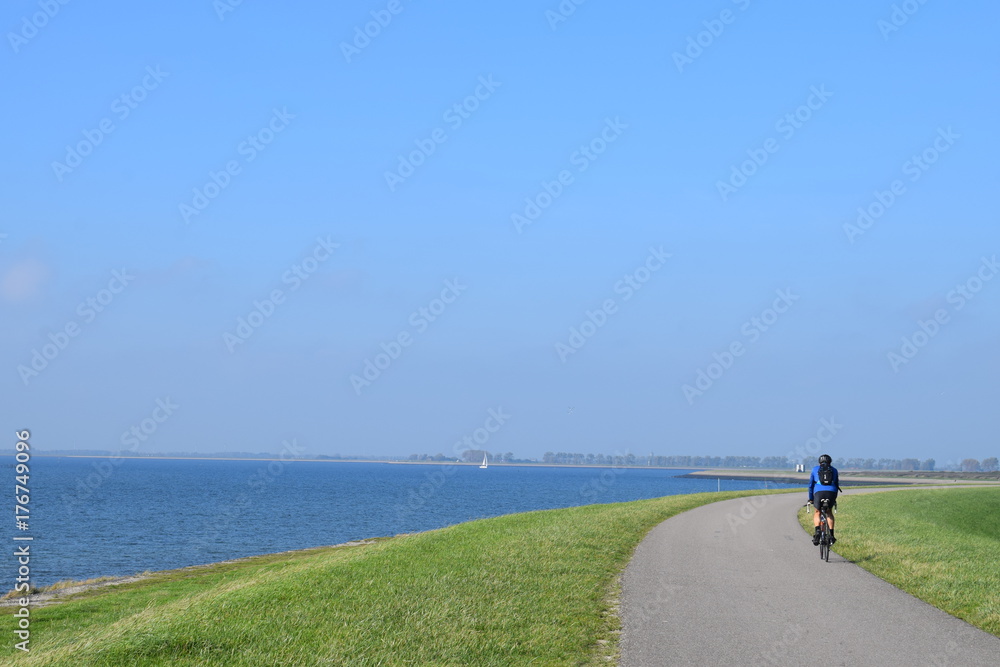 Obraz premium Typical dutch image of people cycling on the dike