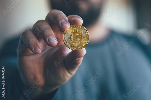 Cryptocurrency golden bitcoin coin in man hand - symbol of crypto currency - electronic virtual money for web banking