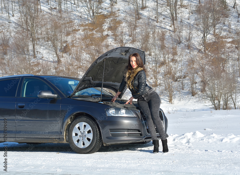  Winter car breakdown - young fashion woman trying to fix the car