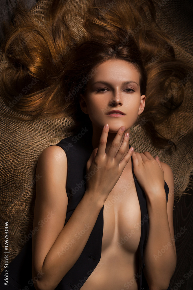 naked sensual girl in unbuttoned vest lies on burlap fabric naked sensual girl in unbuttoned vest lies on burlap fabric