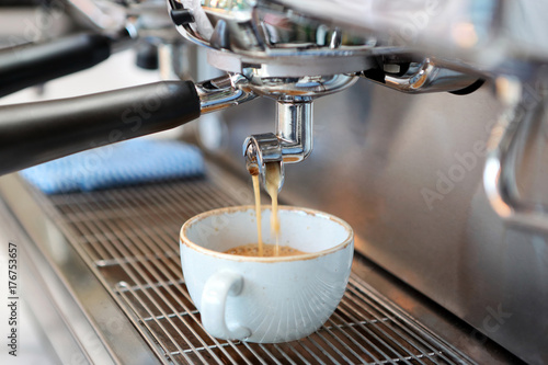 Closeup of cappuccino pouring from professional coffee machine brewing
