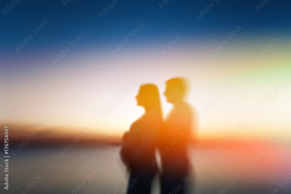 blur pregnant woman and her husband, who gently embraces her on a sunset background.Happy family couple on the beach.