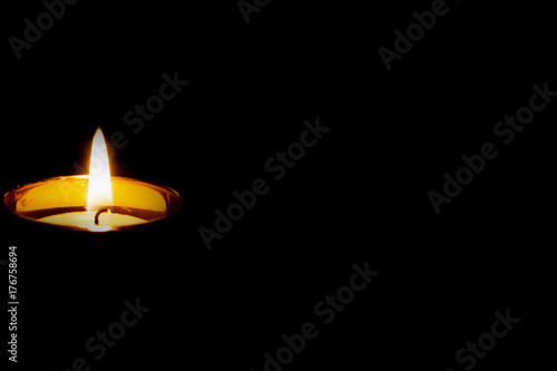 Mourning funeral concept.Single isolated burning candle on black background.