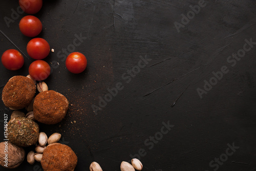 Spicy cheese assortment. Healthy rustic food with free space. Gourmet sorts of dairy with cherry tomatoes on black background