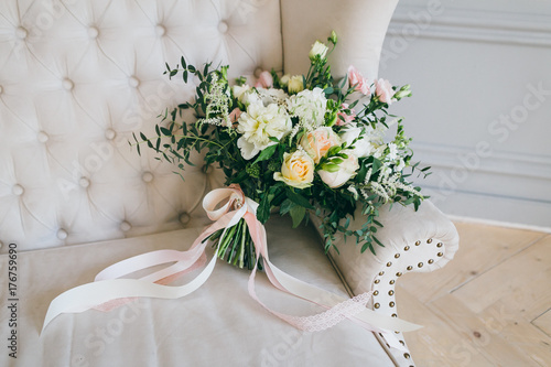 Rustic wedding bouquet with creamy roses and white carnations on a luxury cream sofa. Close-up. Side view