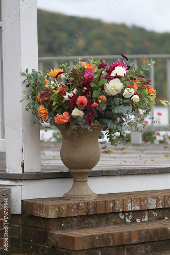 White, Green, Magenta, and Orange Fall Wedding Floral Arrangement in a Stone Urn Outside