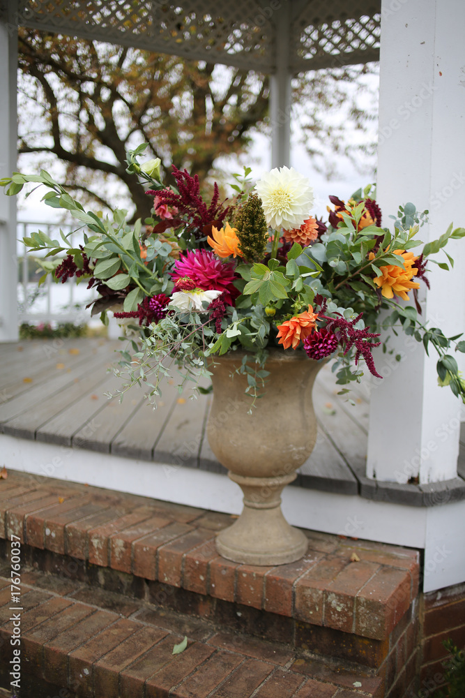 White, Green, Magenta, and Orange Fall Wedding Floral Arrangement in a Stone Urn Outside