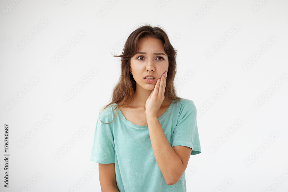Terrified unhappy young female pressing cheek while suffering from toothache. Student girl having frustrated or shocked look, touching face. Human facial expressions, emotions, feelings and reaction Terrified unhappy young female pressing cheek while suffering from toothache. Student girl having frustrated or shocked look, touching face. Human facial expressions, emotions, feelings and reaction