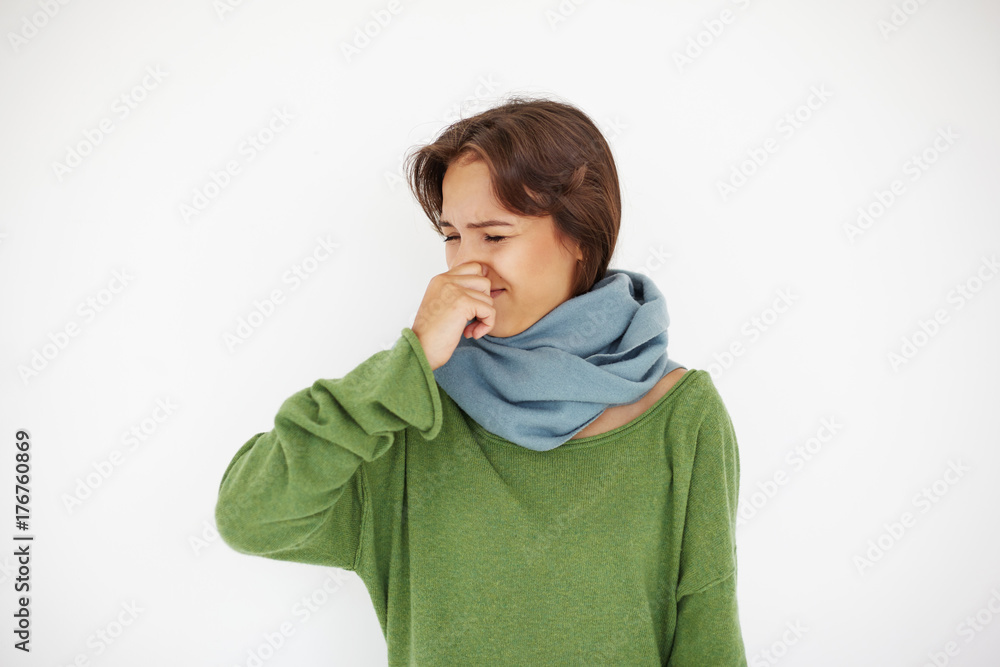 Φωτογραφία Brunette young Hispanic woman wearing warm scarf around her neck having flu, cold or allergy symptoms, pinching her nose while sneezing