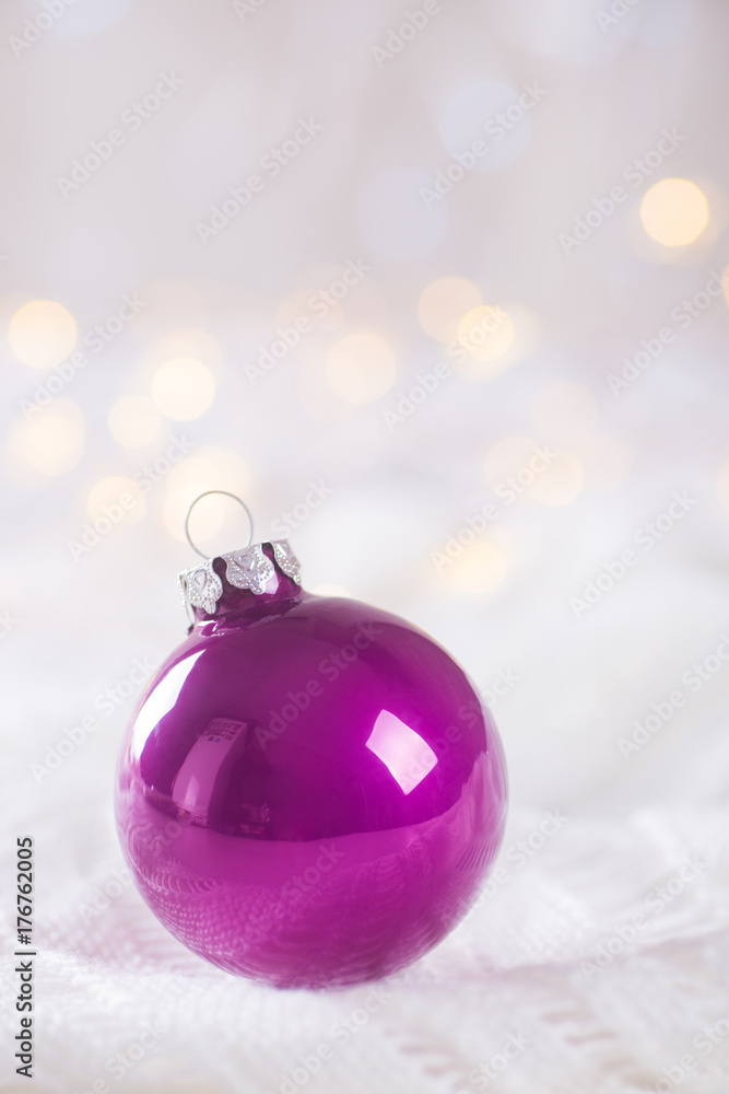 Purple Christmas ball on white lace on light and warm bokeh background Purple Christmas ball on white lace on light and warm bokeh background