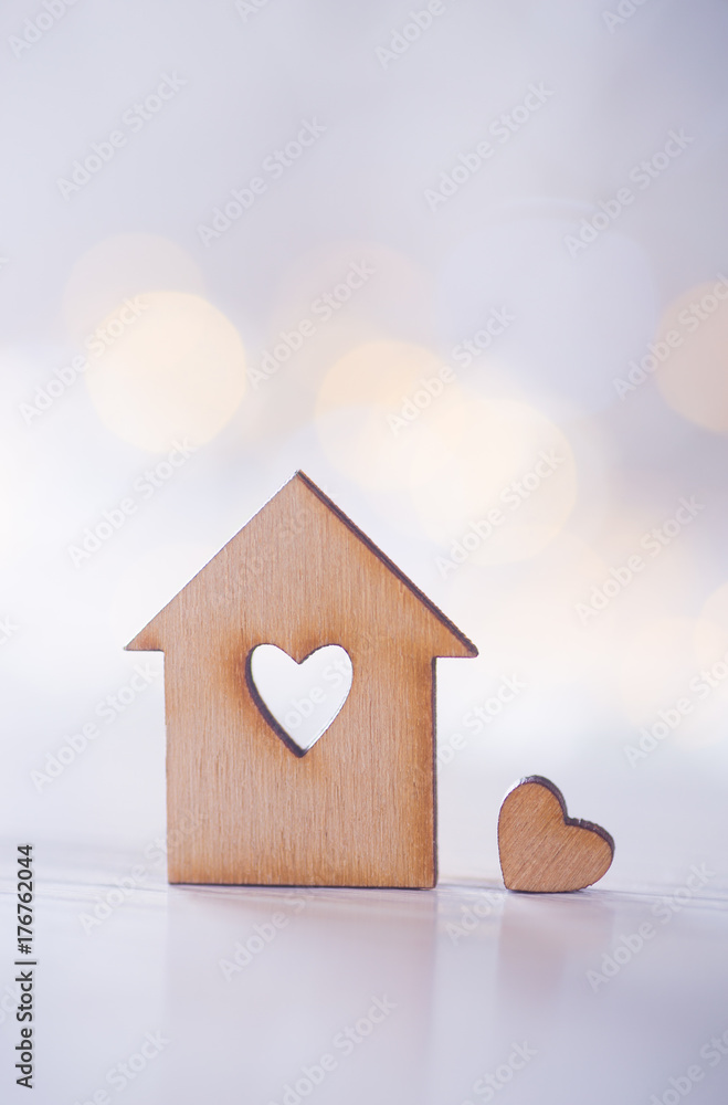 Φωτογραφία Wooden house with hole in the form of heart with little heart on light bokeh bac