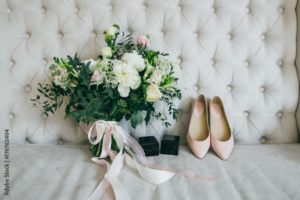 Φωτογραφία Wedding bouquet, pink bridal shoes and black boxes with rings on a luxury sofa