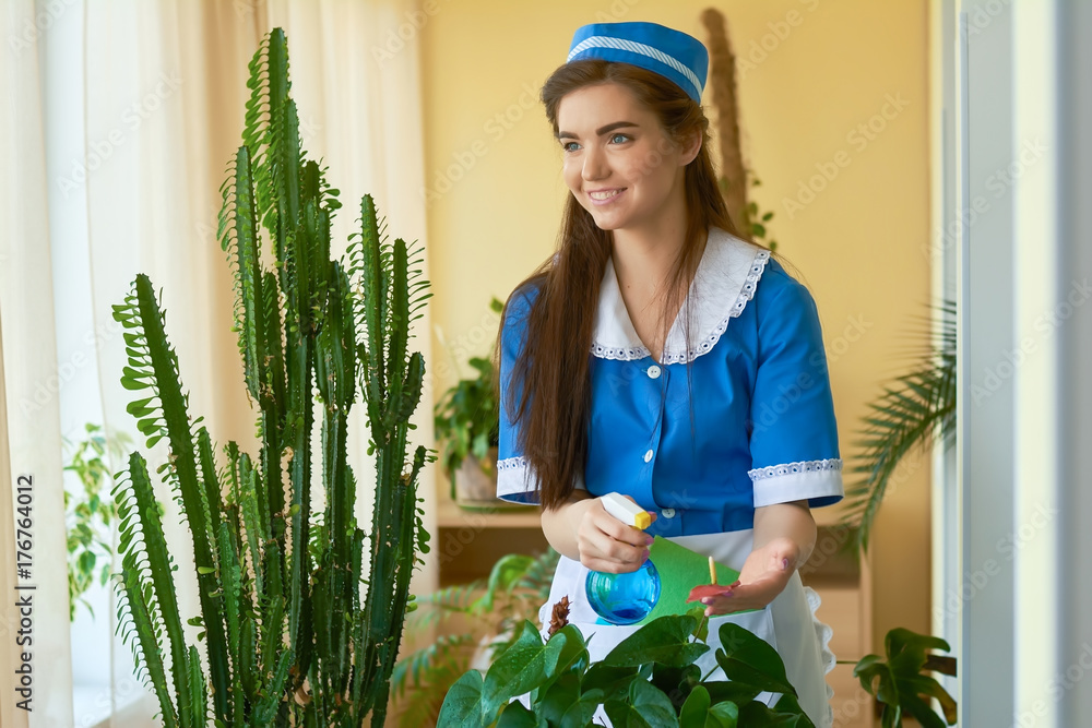 Ταπετσαρία Smiling housemaid at work. Young woman water spraying plant.