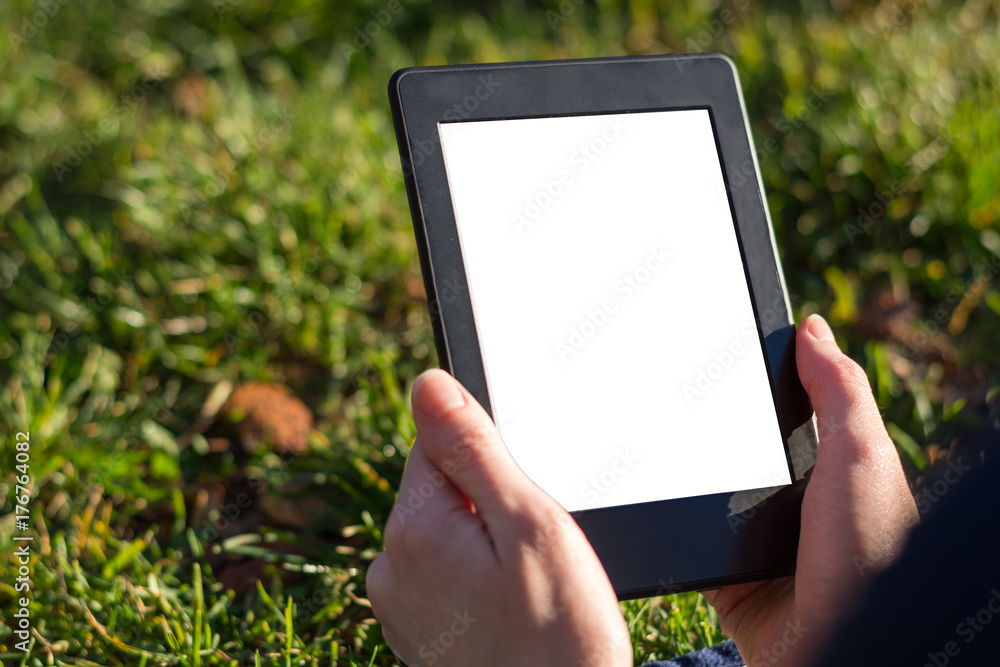 Reading an ebook on a tablet in the park Reading an ebook on a tablet in the park