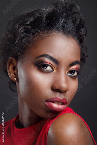 Closeup studio portrait of a girl African women with bright make-up and glossy skin on black isolated background