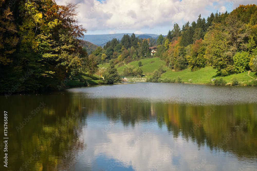 The bright autumn colors of the forest are reflected in the lake.
