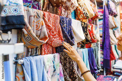 Young Woman Shopping For A New Scarf and choosing colorful fabric in bazar