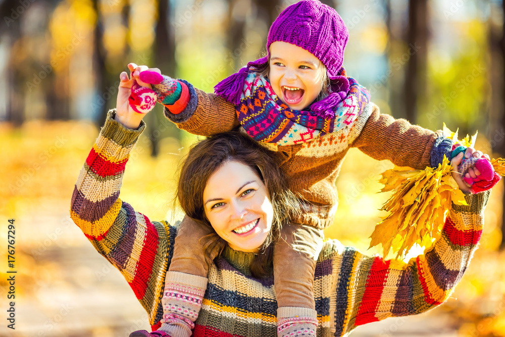 Little girl playing with mother in the autumn park