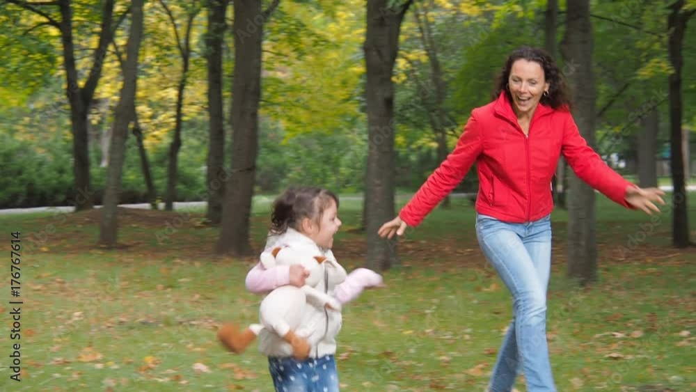 Happy family playing in the park. Mother and daughter are running around in the autumn park. Happy family playing in the park. Mother and daughter are running around in the autumn park.