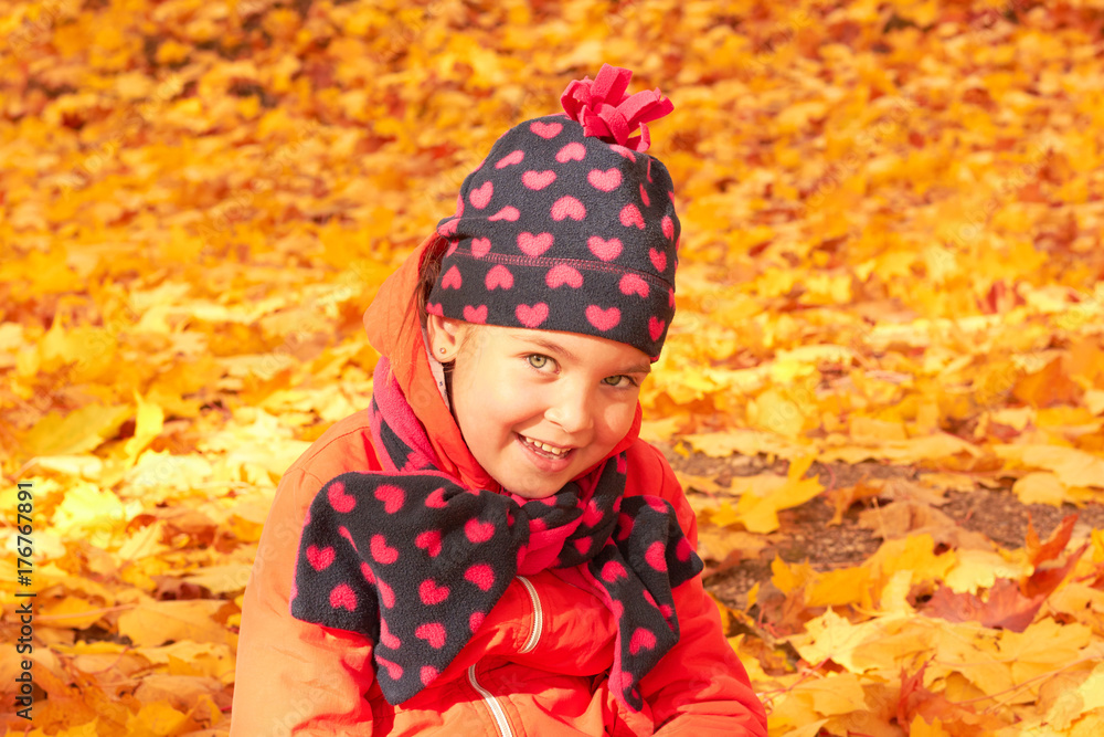 Cute baby sitting on yellow leaves in autumn park