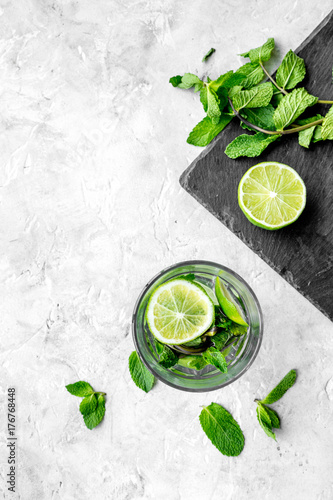 Glass of mojito, lime, mint on grey stone background top view copyspace