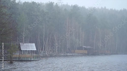 The snowfall on the lake. Mooring on Lake at heavy snowfall. Simple landscape. Late spring snow fall reflects on our favorite pond. Snow is falling in the water photo