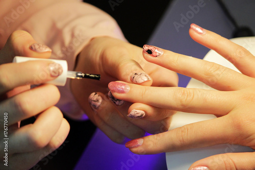 A student at the training courses of manicure applies final protective layer.