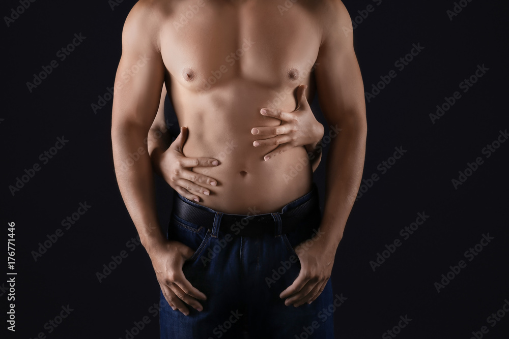 Female hands touching body of sporty young man on dark background Female hands touching body of sporty young man on dark background