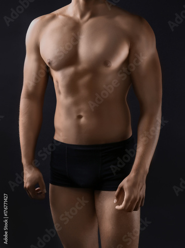 Sporty young man on dark background © Africa Studio