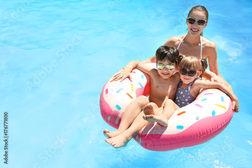 Young woman and her children with inflatable donut in swimming pool