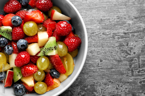 Bowl with yummy fruit salad on grunge table