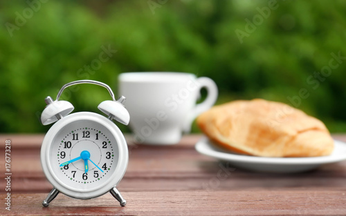 Clock alarm on wooden table outdoors. Morning routine concept