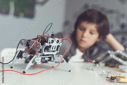 The boy creates a robot. He measures his data with a multimeter. The boy observes the measurements
