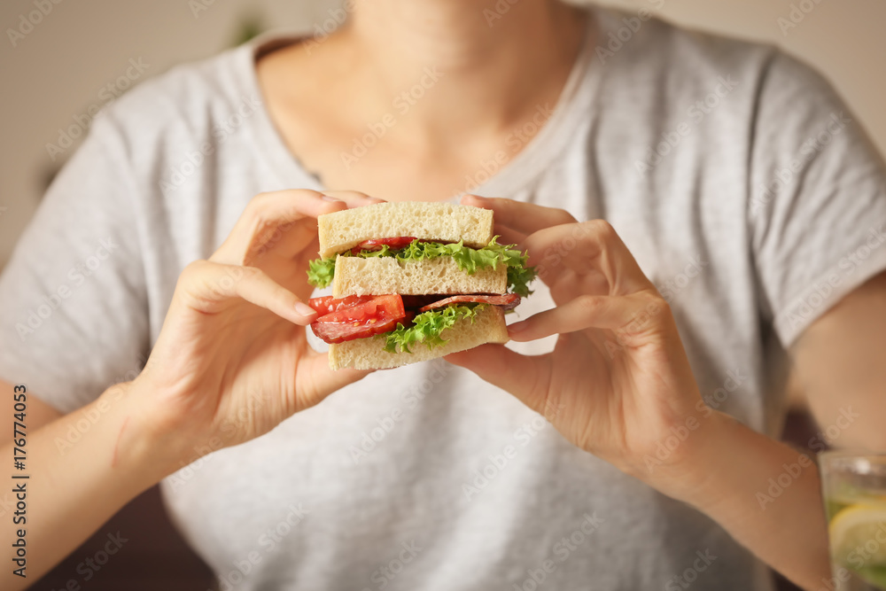 Woman holding delicious sausage sandwich indoors Woman holding delicious sausage sandwich indoors