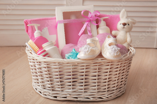 Wicker basket with baby shower gifts on floor indoors