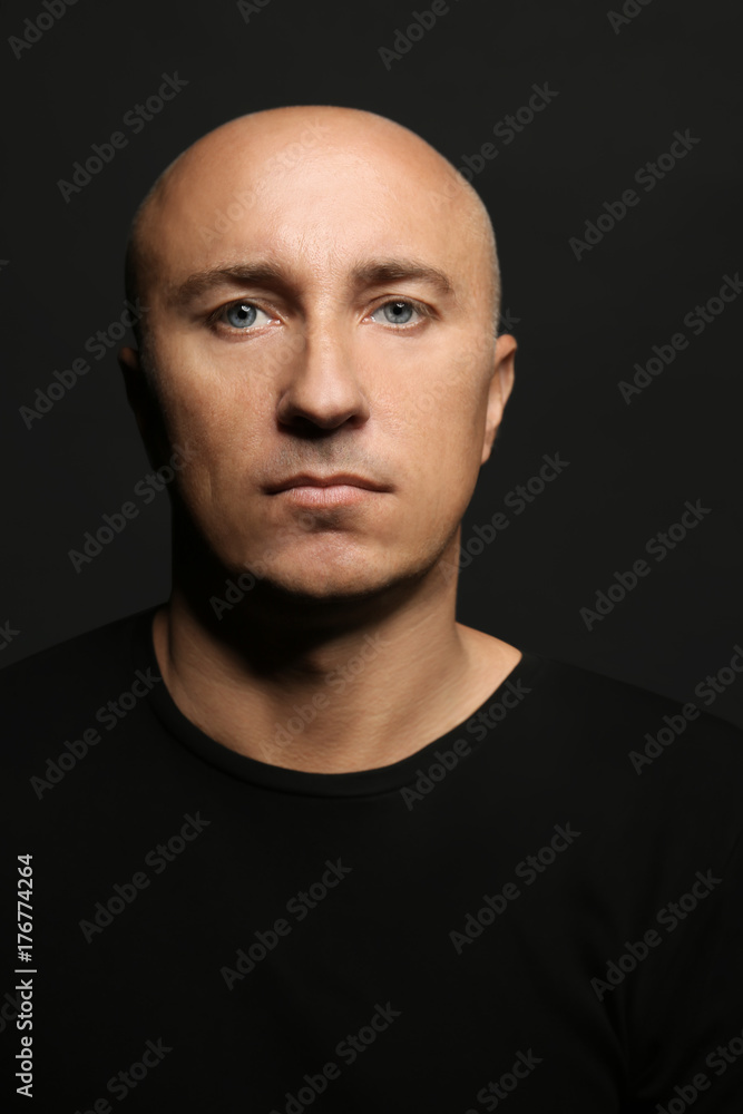 Bald man in t-shirt on black background