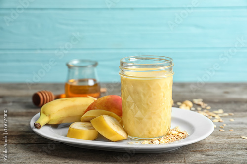 Jar with protein shake and plate with fruits on table