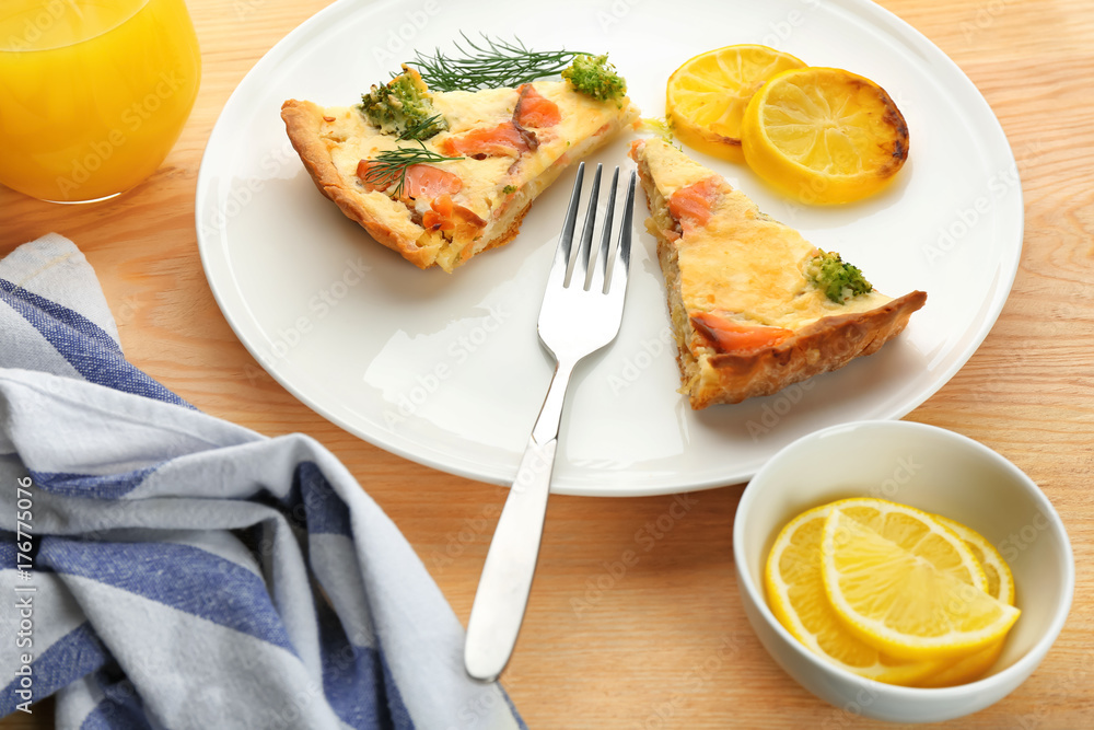 Plate with pieces of salmon quiche pie on table