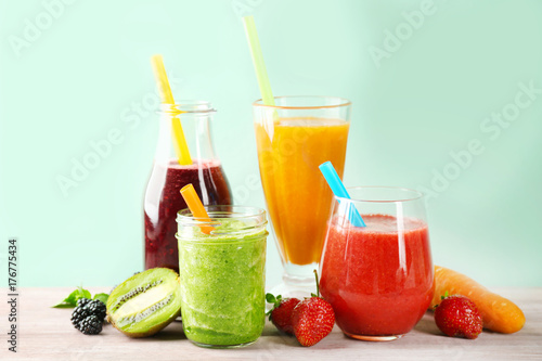 Glassware with delicious smoothies on table against color background