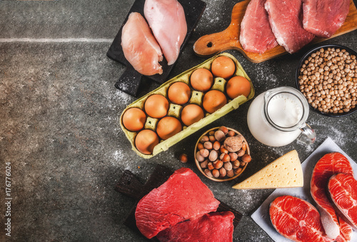 Healthy food background. Selection of protein sources: beef and pork meat, chicken  filet, salmon fish, egg, beans, nuts, milk. Top view copy space, dark background photo