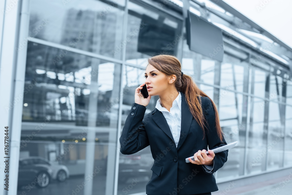 Successful businesswoman or entrepreneur using a digital tablet computer and talking on cellphone standing in front of his office. Successful businesswoman or entrepreneur using a digital tablet computer and talking on cellphone standing in front of his office.