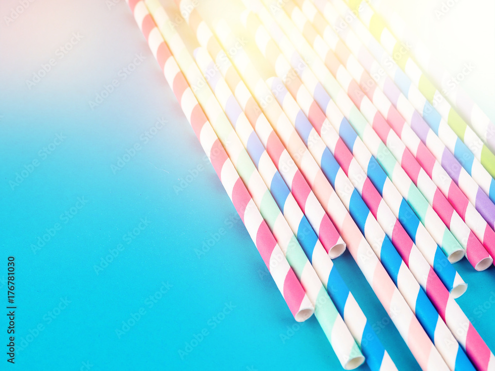 Naklejka premium Drinking straws for party on blue pastel background with copy space. Top view of colorful paper disposable eco-friendly straws for summer cocktails.
