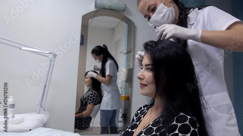 In the clinic, the cosmetologist makes mesotherapy injections to the client to improve the condition of the hair photo