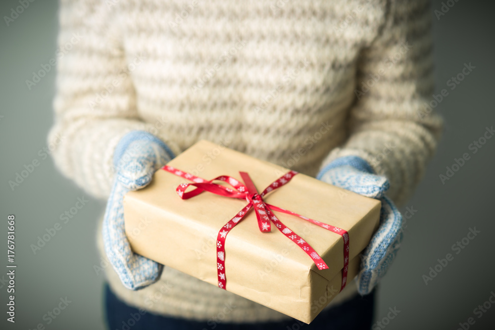 Christmas background. A girl in a warm knitted sweater and mittens is holding a Christmas present. Gifts for men. Merry Christmas. Gift for a girl. Knitted mittens. Knitted dress. Box with gifts. Christmas background. A girl in a warm knitted sweater and mittens is holding a Christmas present. Gifts for men. Merry Christmas. Gift for a girl. Knitted mittens. Knitted dress. Box with gifts.