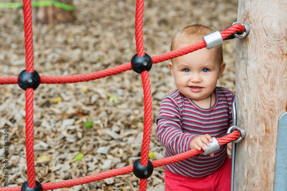 Outdoor portrait of adorable baby girl having fun on playground, cute little 9-12 months child playing outdoors Outdoor portrait of adorable baby girl having fun on playground, cute little 9-12 months child playing outdoors