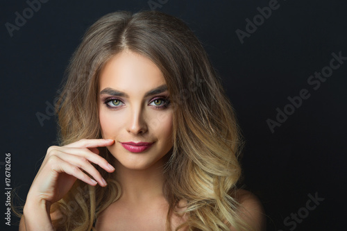 portrait of a smiling beautiful young girl with makeup and hairdress on head on a black background