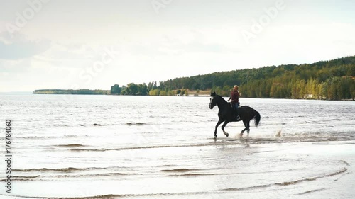 young pretty girl riding horse in river water photo