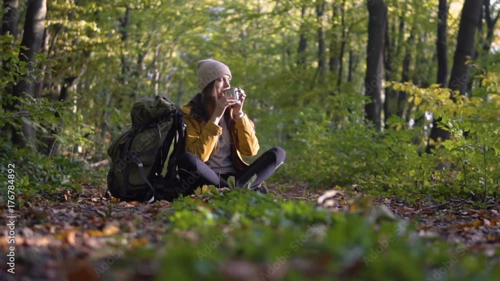 Female skinny tourist is having tea and taking the map out of the backpack in the wood, slowmotion on fall day Female skinny tourist is having tea and taking the map out of the backpack in the wood, slowmotion on fall day