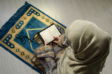 Muslim woman praying for Allah muslim god at room near window. Hands of muslim woman on the carpet praying in traditional wearing clothes, Woman in Hijab, Carpet of Kaaba, Selective focus