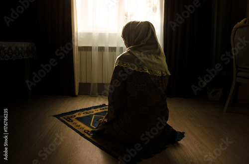 Fotografía Muslim woman praying for Allah muslim god at room near window